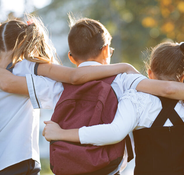 school friends a boy and two girls with school backpacks on their backs walk after class