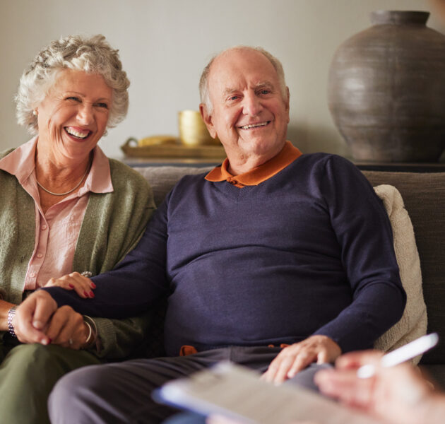 Elderly patients engaging with medical practitioner for health advice and insurance guidance. Senior couple attentively listening to a psychologist woman during consultation at home. Caring female social worker explaining health matters to an elderly couple at home.