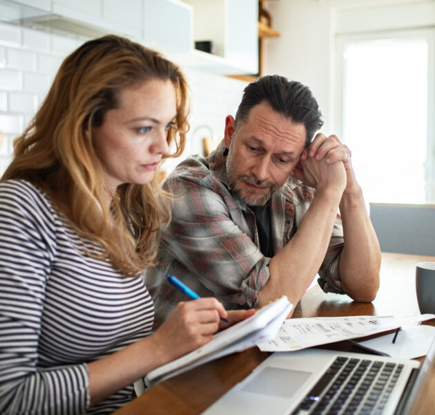 Stressed couple reviewing bills and finances at kitchen table